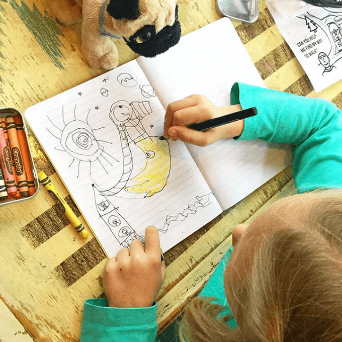 A young girl drawing with pencil and crayons