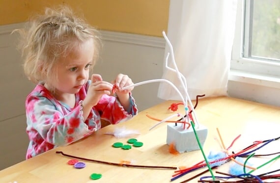Child stringing button onto pipe cleaner for 3D wire sculpture