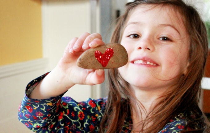 child with glitter heart rock
