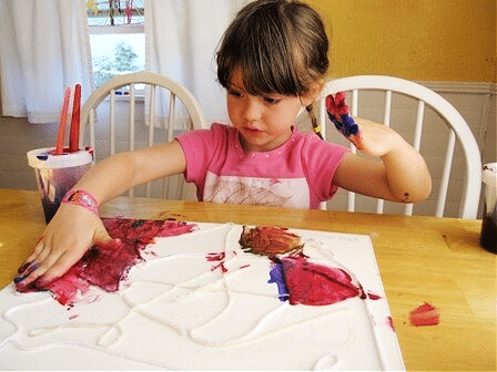 Child using her hands to paint yarn