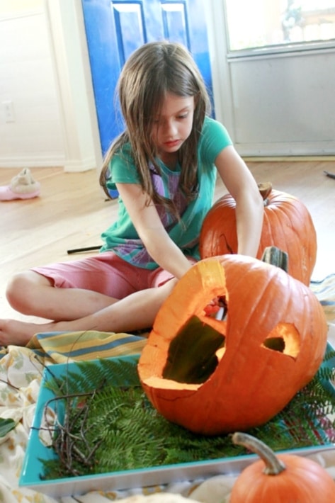 child carving out a pumpkin