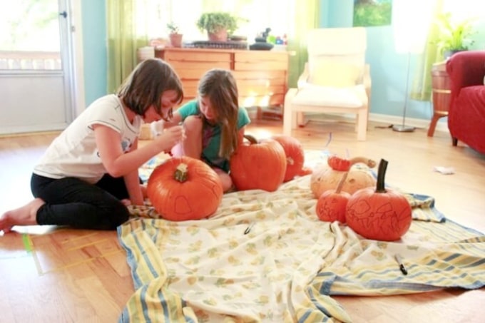 girls drawing fairy houses on pumpkins