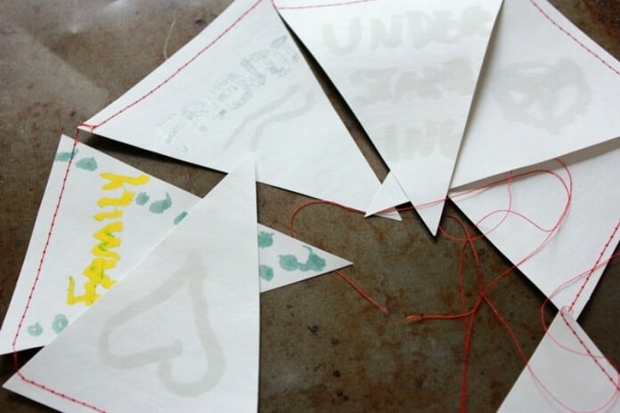 Paper buntings with melted crayon drawings and doodles of an adult.