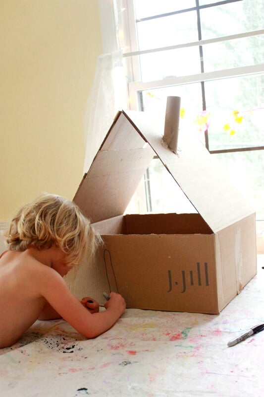 girl drawing on cardboard box dollhouse