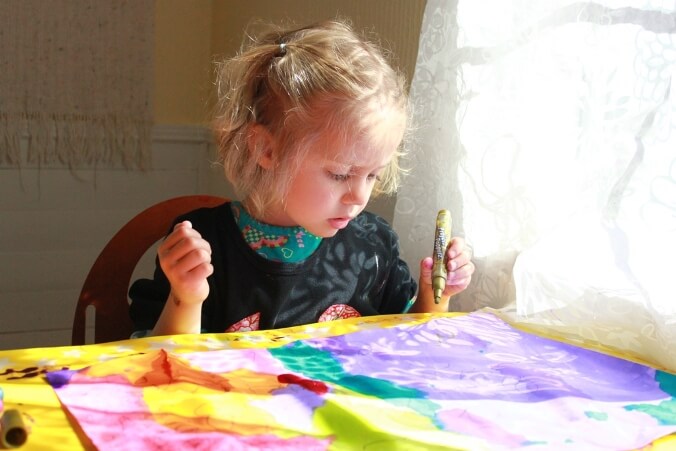 A young girl painting over her shadow tracings.