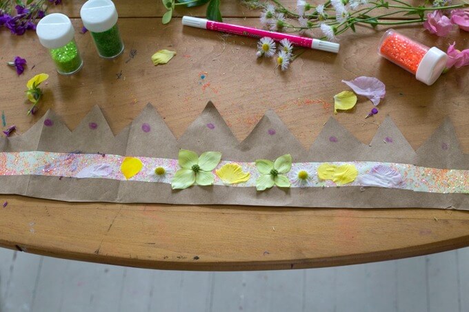 A simple paper bag flower crown made by a child and decorated with markers and glitter.