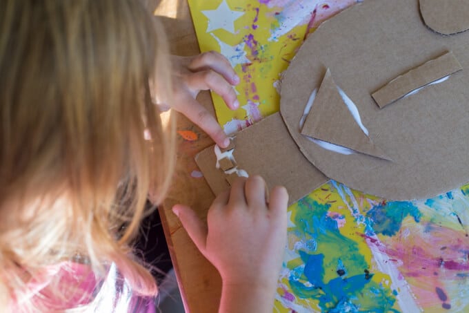 A young girl gluing cardboard shapes together for the 3D cardboard portrait.