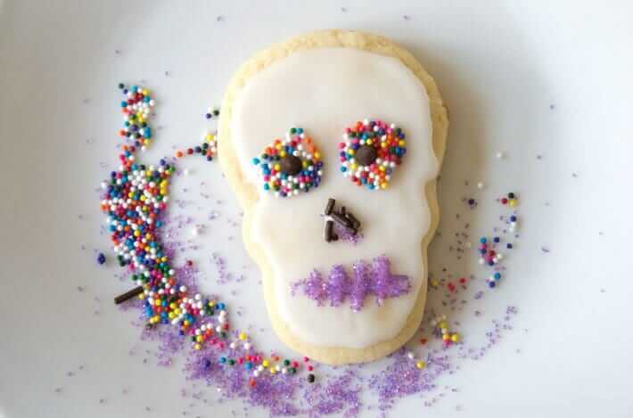 Decorating sugar skull cookies with little candies and sprinkles