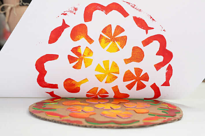 Printing mandala pizza prints - a fun and easy printmaking idea for kids. This image shows the print being lifted off of the handmade printing plate.