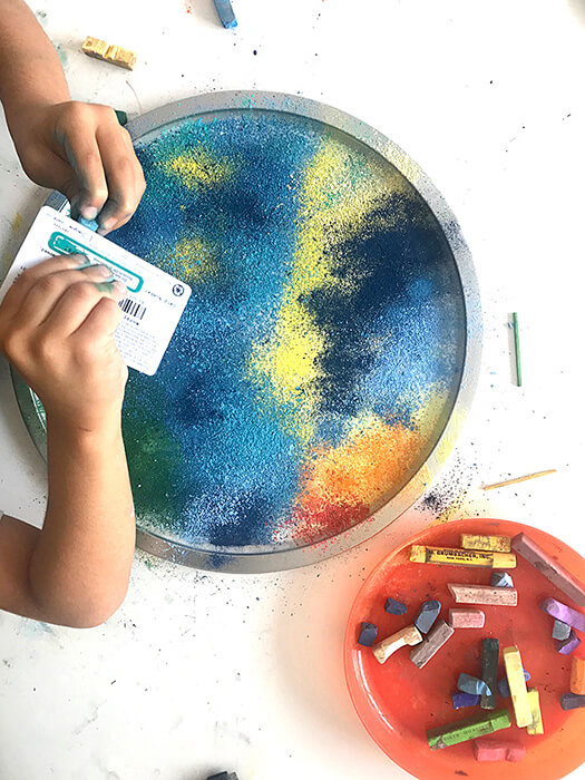 Scraping chalk pastels with a plastic card for an easy chalk art activity.