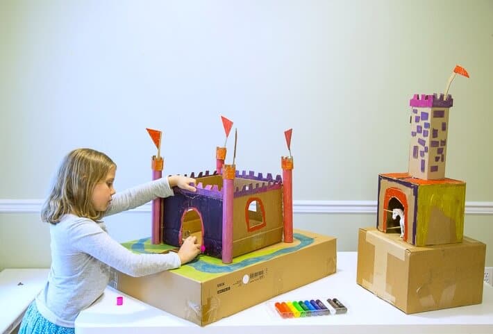 Daphne coloring the cardboard castle with paint sticks