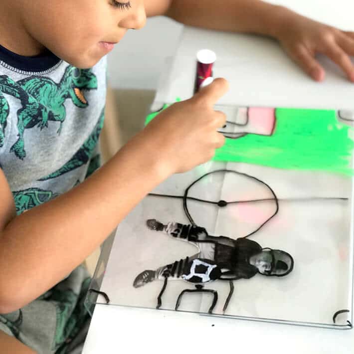 Boy drawing creating mixed media artwork on plexiglass