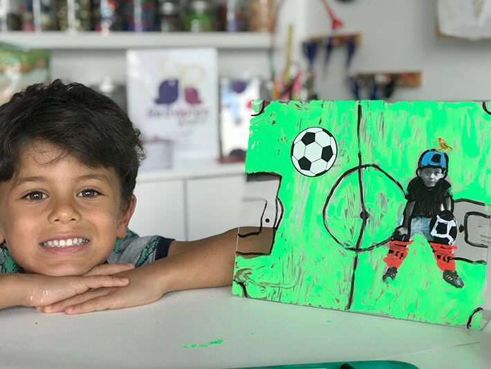 Boy posed next to finished mixed media artwork on plexiglass