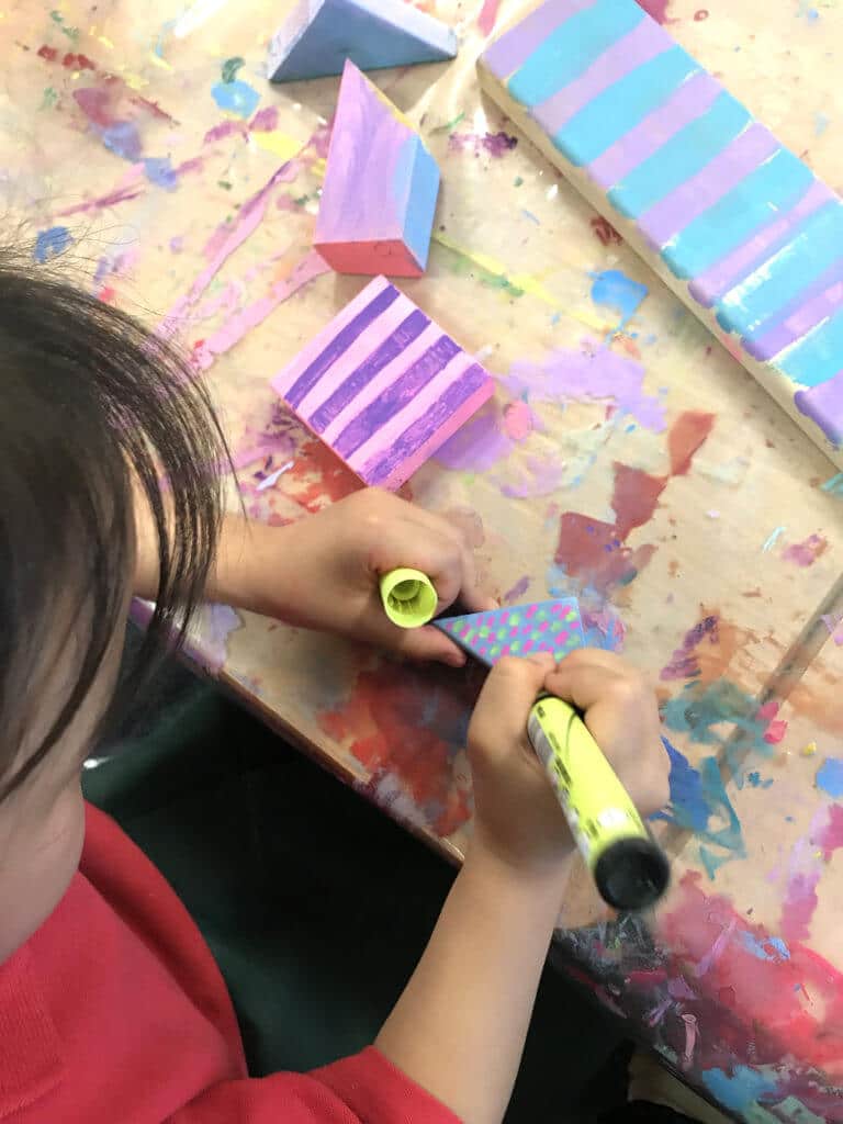 Child painting patterns on wood blocks