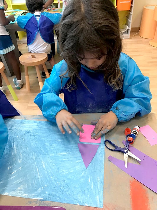 Girl glueing shapes on paper for city mixed media project – Paul Klee Art for Kids