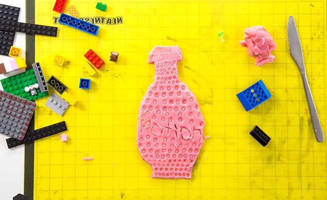 LEGO prints made in playdough – playdough potion bottle with LEGOS and butter knife on mat