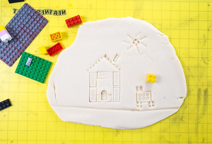 LEGO prints of house scene imprinted on playdough with LEGOs on mat