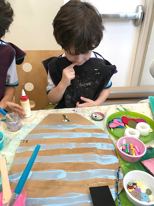 Boy creating animal mask for kids with blue stripes on cardboard