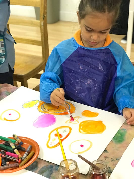 Boy painting colorful circles with watercolor paint for Yayoi Kusama Inspired Dot Paintings for Kids