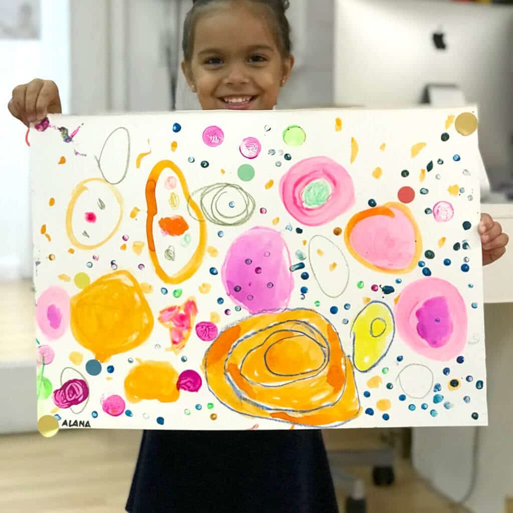 Child holding up colorful Yayoi Kusama Inspired Dot Painting