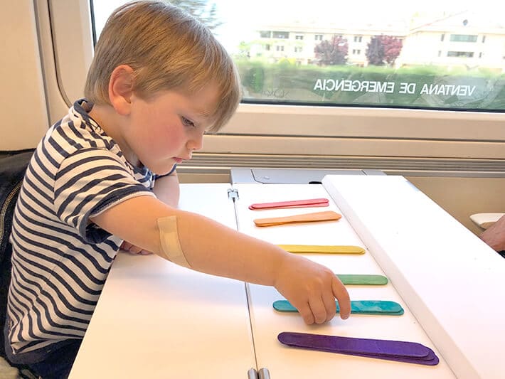 Traveling with toddlers art activities – boy color sorting popsicle sticks on train