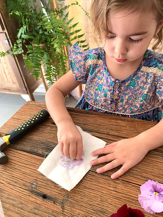 Child peeling off flower from canvas to create flower flags