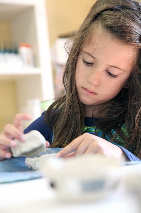 Child making an air dry clay bowl for mosaic art for kids