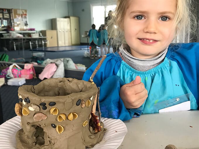 Girl sitting next to finished clay fairy house