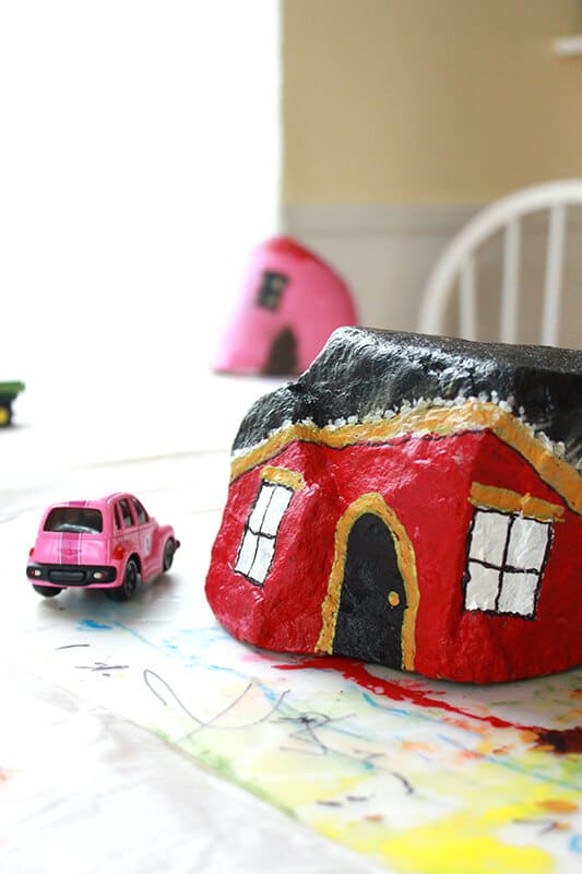 Red painted rock house with pink car on road map