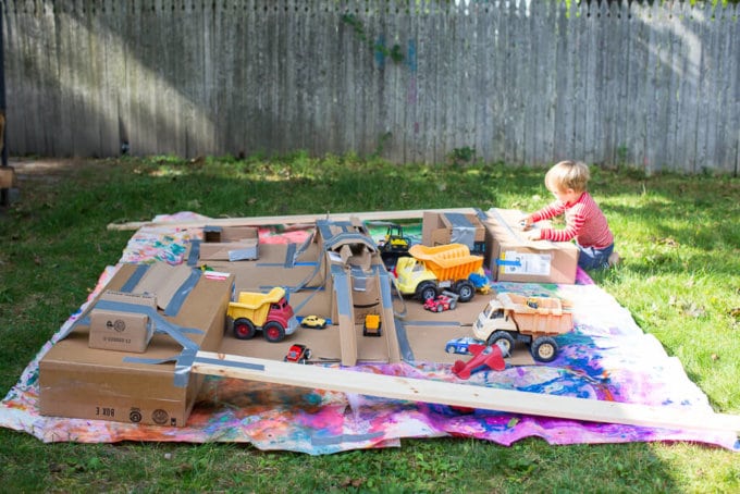 A cardboard tunnel and ramp setup for painting with wheels for kids art activity