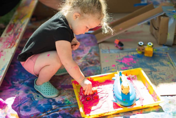 A child pushing a car through paint for an action art activity