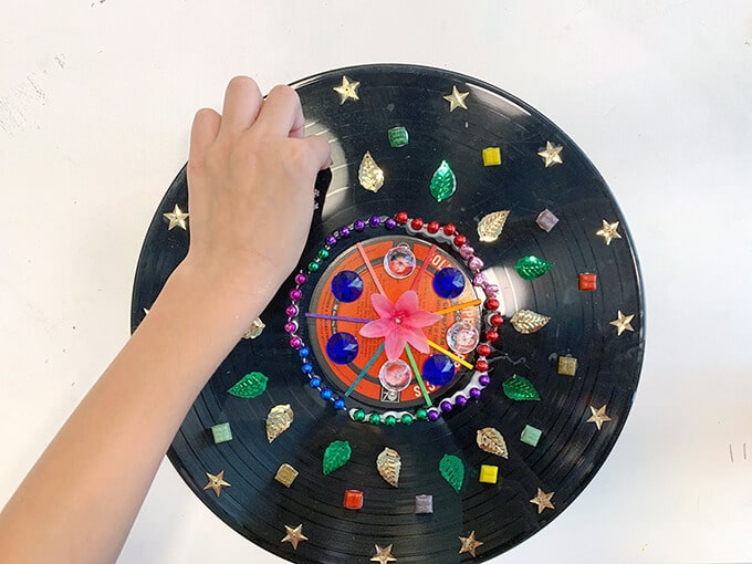 Child adding art materials to record for mandala art project