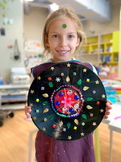 Child holding up finished record mandala for kids