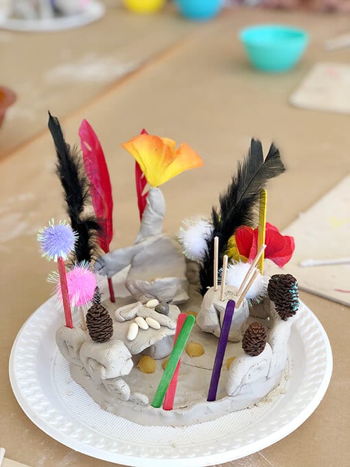 Clay small world for kids with feathers, sticks and pom poms
