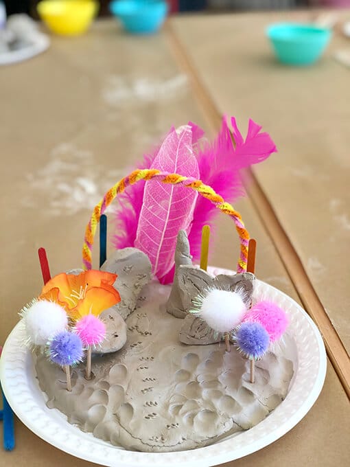 Small worlds in clay for kids with pom poms, feathers and rainbow