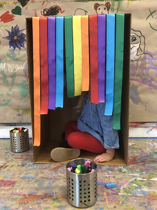 Child in box with hanging rainbow ribbons