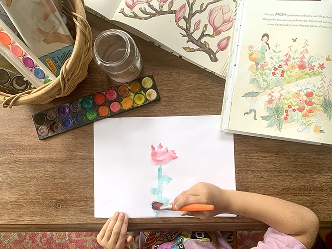 Child painting red flower with watercolor paint set