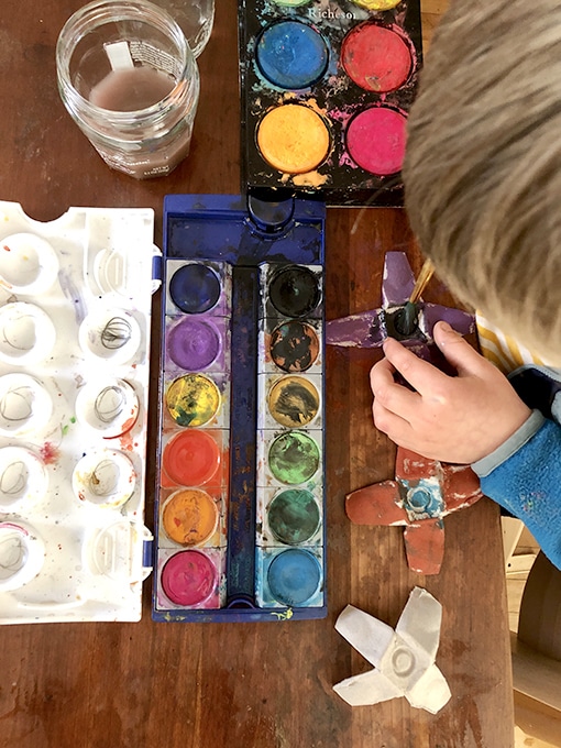 Child painting egg carton flowers