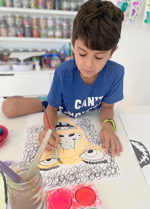 Child painting watercolors on portrait