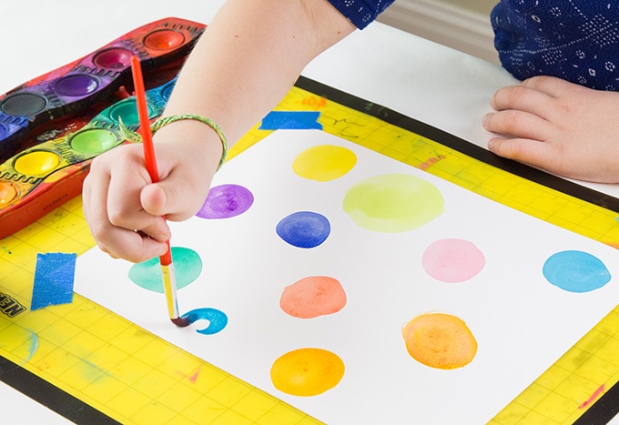 Child-painting-watercolor-dots-on-white-paper