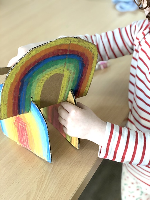 Child attaching two cardboard rainbows together