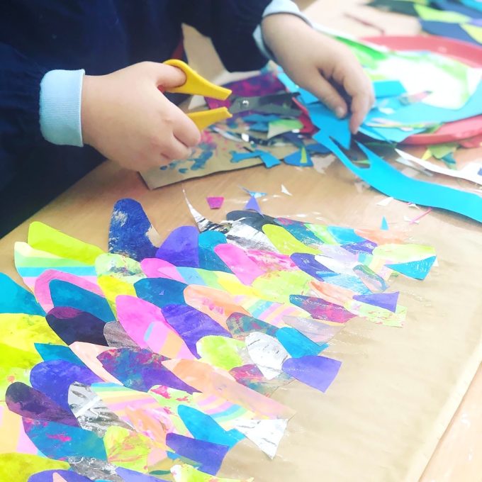 Child cutting out paper feathers for DIY wings for kids
