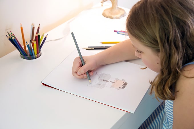Child drawing with colored pencils at desk