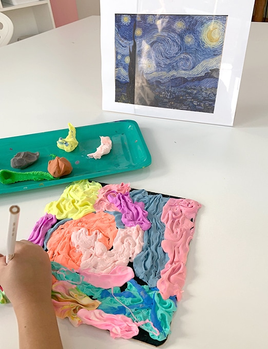 Child pressing pencil and creating texture in colored air dry clay