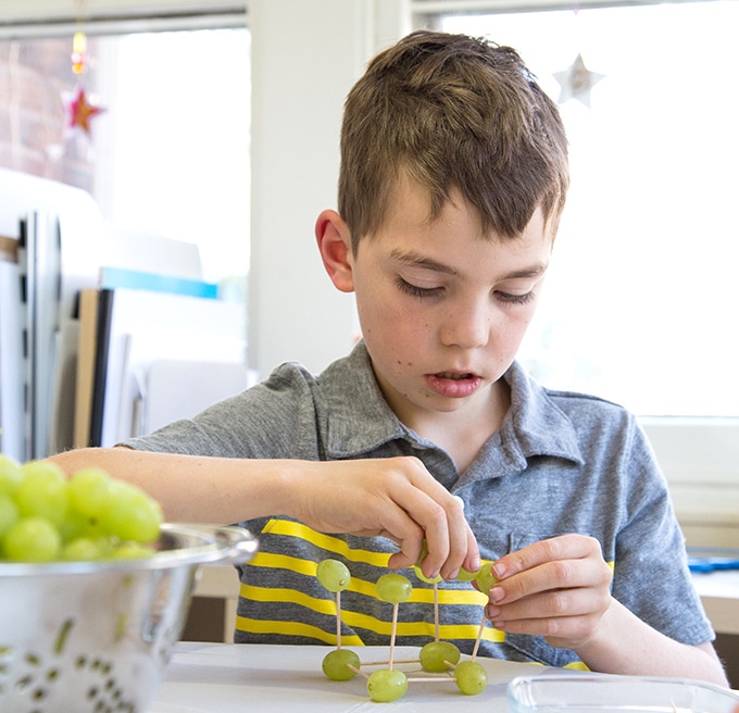 Child creating grape and toothpick sculpture
