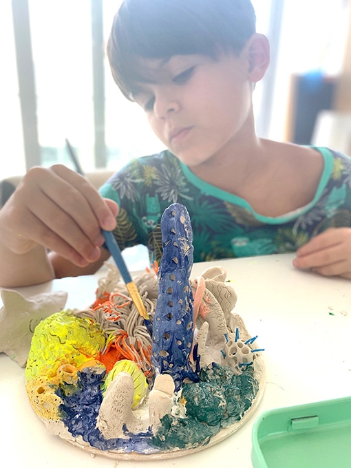 Child painting clay sculpture