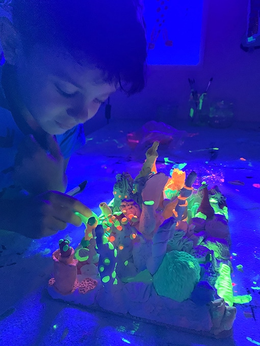 Child with glow in the dark coral reef