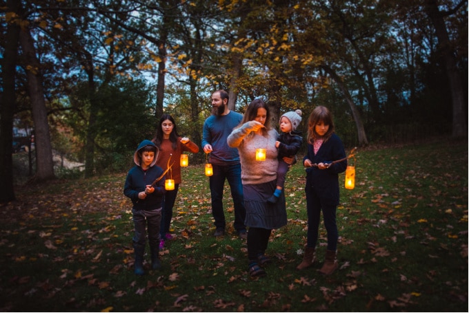 Family standing with DIY lanterns on candlelit nature walk.