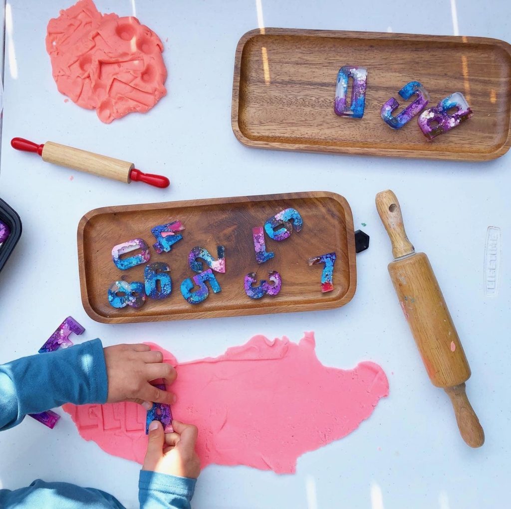 Child pressing resin letters in to playdough for literacy building activity – Little Mainer Studio