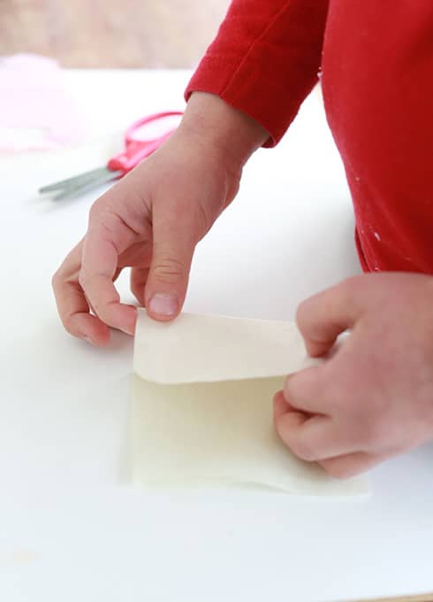 Child folding rectangular piece of tissue paper